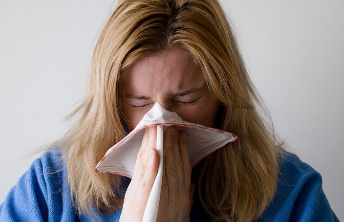 Woman Blowing Nose into Tissue