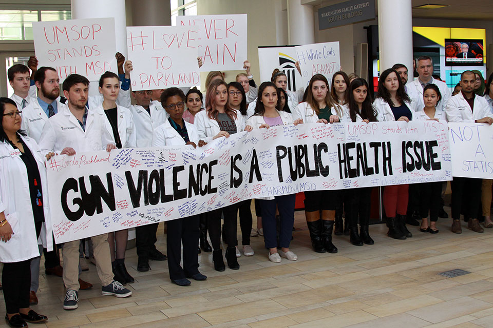 Faculty, Staff, and Students Pose with Banner that Reads, "Gun Violence is a Public Health Issue."