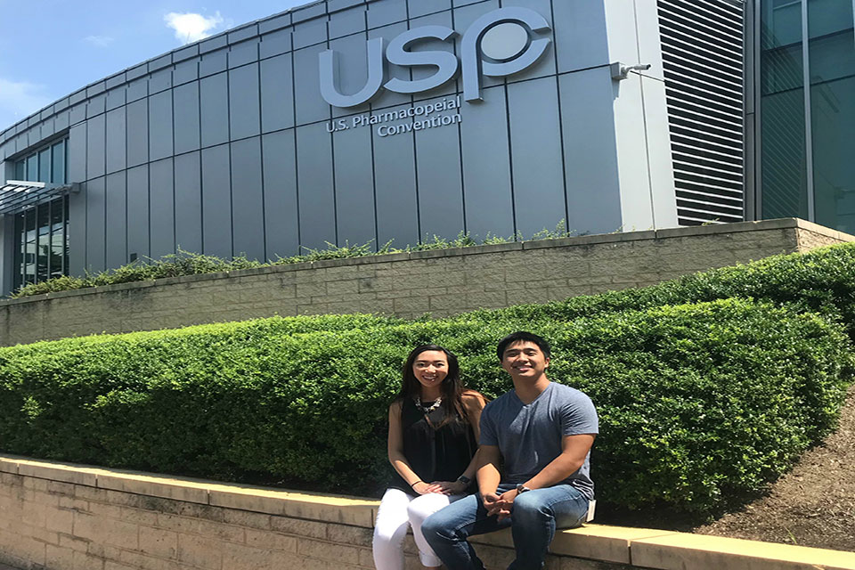 Second-year student pharmacist Michelle Nguyen and third-year student pharmacist Khang Nong pose for photo in front of the USP.