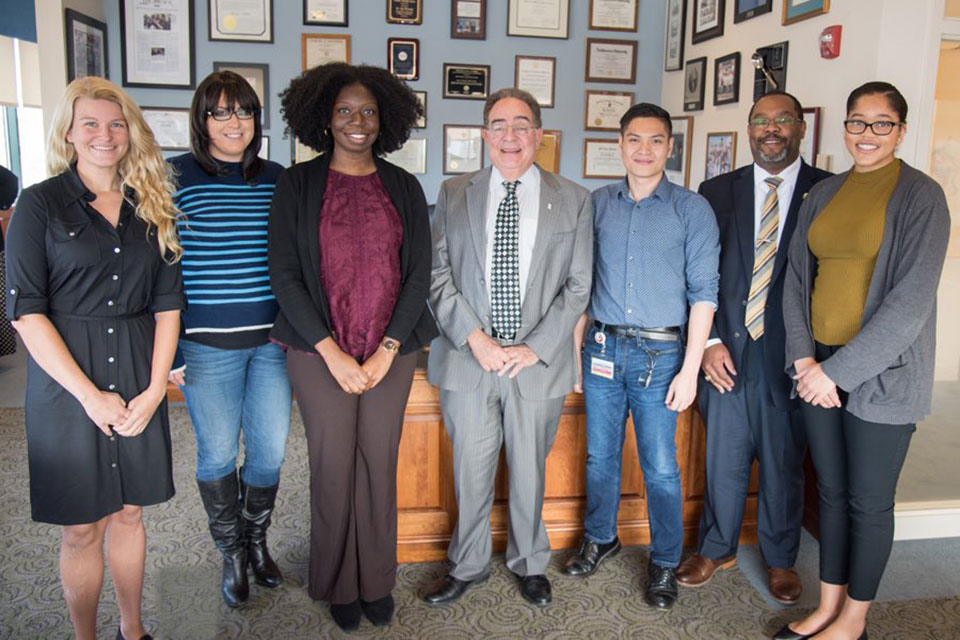 Student pharmacist Chigo Oguh poses with her team members and UMB President Jay A. Perman, MD.