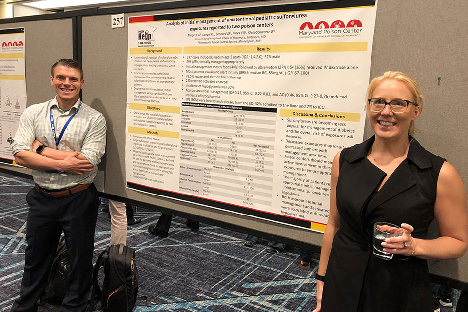 Drs. James Leonard and Elizabeth Hines pose for photo in front of one of the MPC's posters at NACCT.