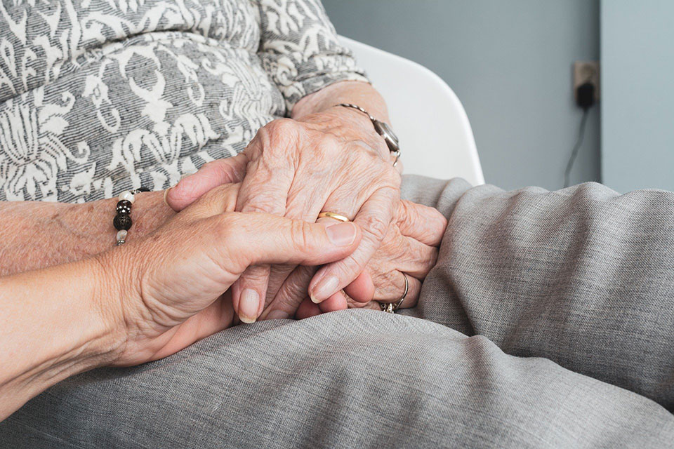 Caregiver holds hands with patient.