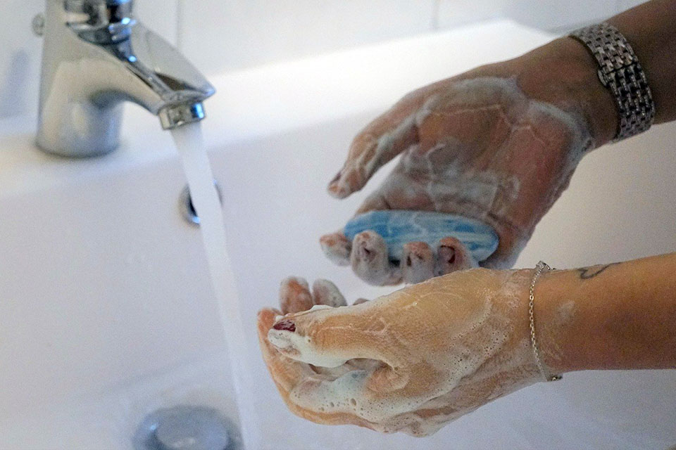 Hands lathered in soap under a running faucet.