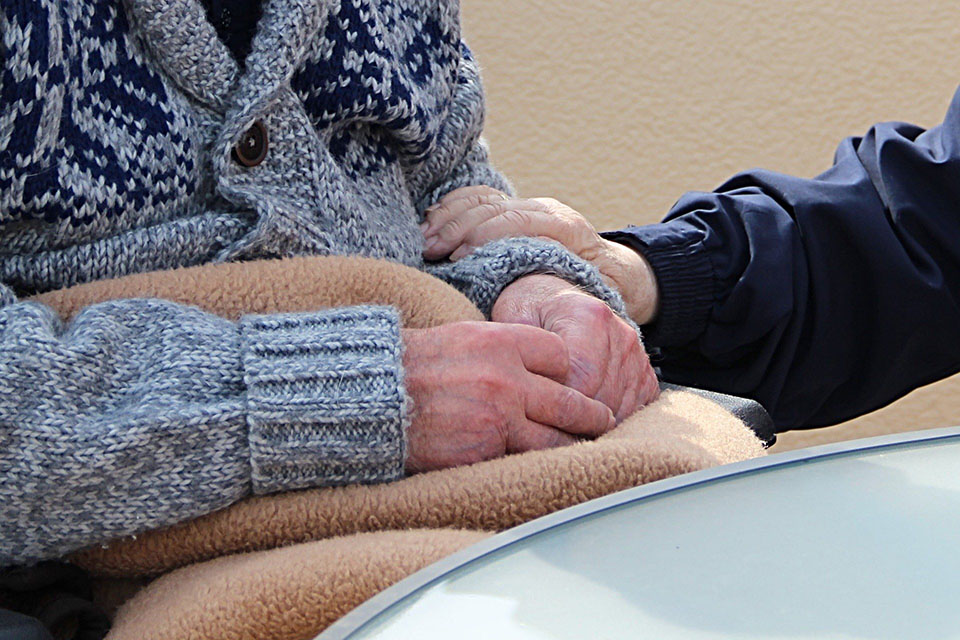 Caregiver embraces the arm of an older adult patient.