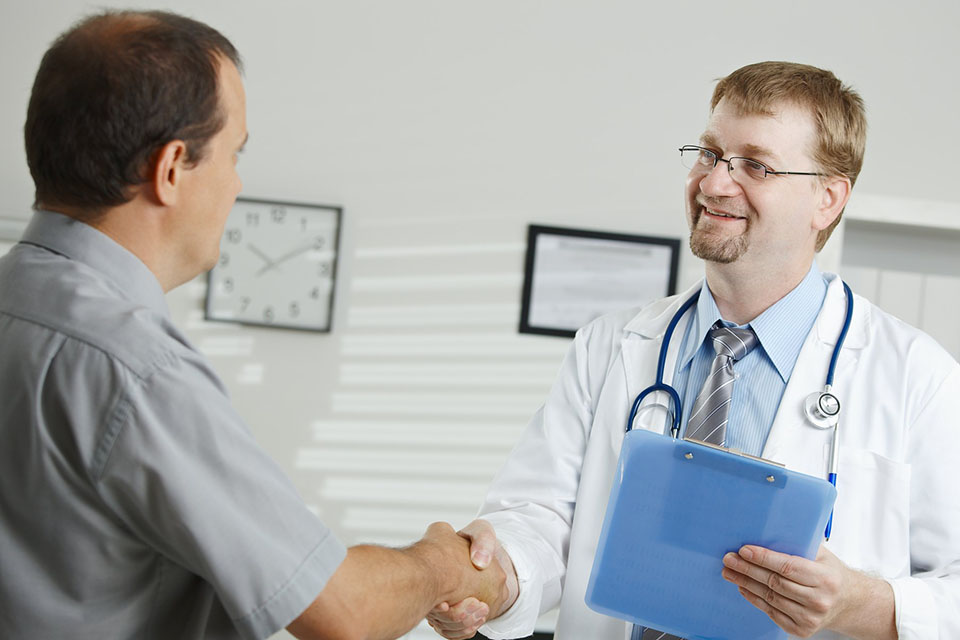 Doctor shakes hand with patient in his office.