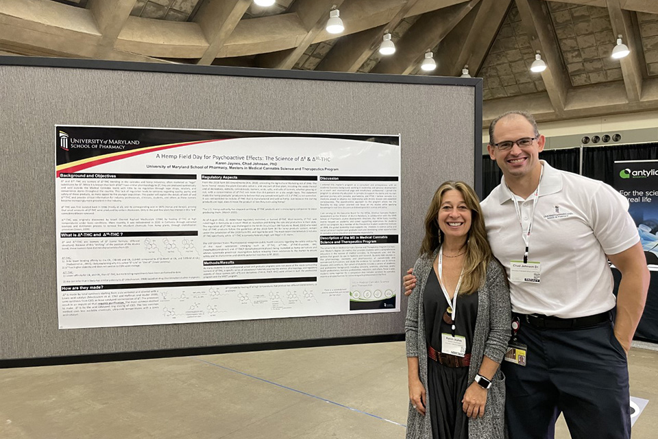 Karen Jaynes and Chad Johnson stand next to a poster at a conference.