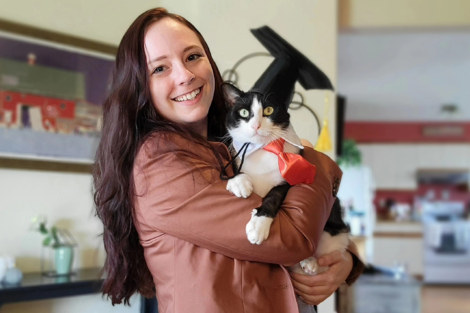 Allison Dunn holds her cat, Murphy, which is wearing a graduation cap.